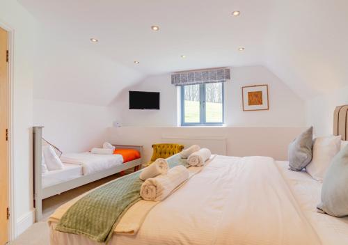 a white bedroom with two beds and a tv at USK Barn in Llanbadoc