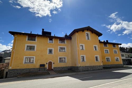 un edificio giallo sul lato di una strada di Cà Val Forno - Vacanze con stile a Maloja