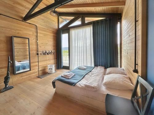 um quarto com uma cama grande e uma janela grande em Eco Saguramo Chalet em Saguramo