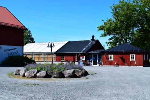 a red barn with rocks in front of a building at Närebo Gårdshotell & Restaurang in Lidköping