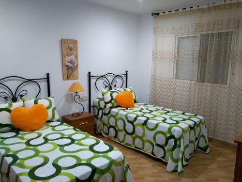 2 Betten mit grünen und weißen Decken in einem Zimmer in der Unterkunft El Capricho de Mamá - Chalet con piscina in Barbate