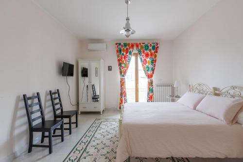 1 dormitorio con cama, sillas y ventana en B&B Vigna del Duca en Grassano