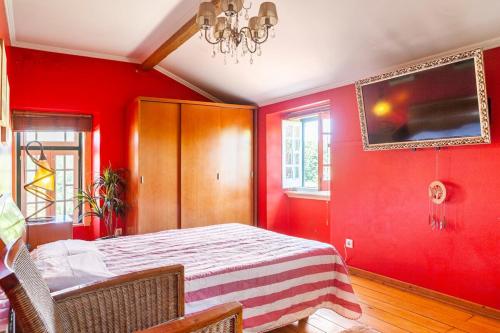 a bedroom with red walls and a bed and a chandelier at B&B Quarto Vermelho Estilo Moderno in Ramalhal