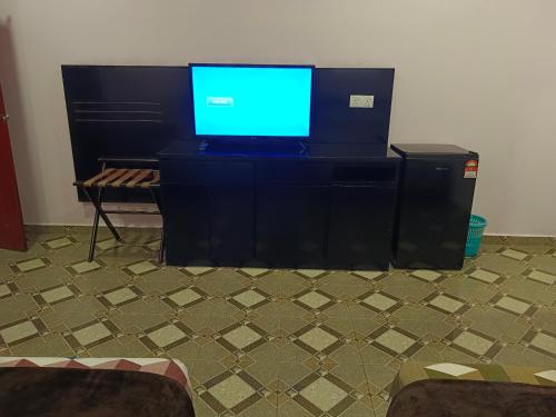 uma televisão em cima de uma cómoda preta em Alfa Roomstay em Pantai Cenang