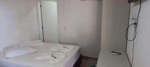 Un dormitorio con una cama blanca con toallas. en Pousada Casa Amarela Brisa Parque, en Penha
