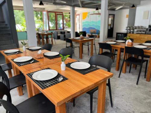 a dining room with wooden tables and chairs at Si! Beach House in Dhiffushi