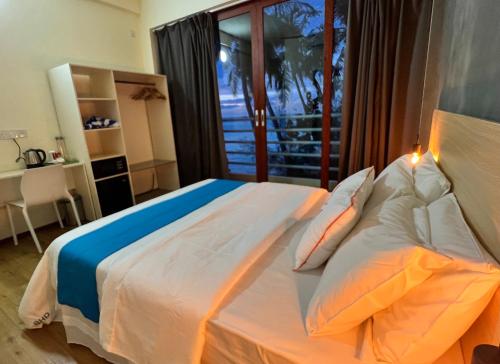 1 dormitorio con 1 cama blanca grande y balcón en Si! Beach House, en Dhiffushi