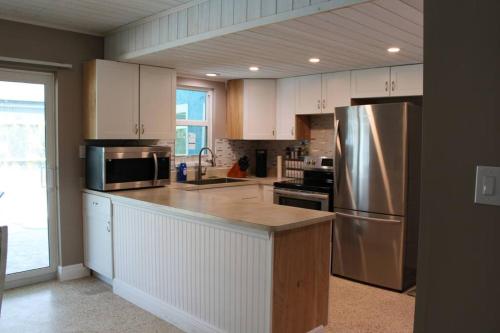 La cuisine est équipée de placards blancs et d'un réfrigérateur en acier inoxydable. dans l'établissement Pool house in Port Charlotte, à Port Charlotte