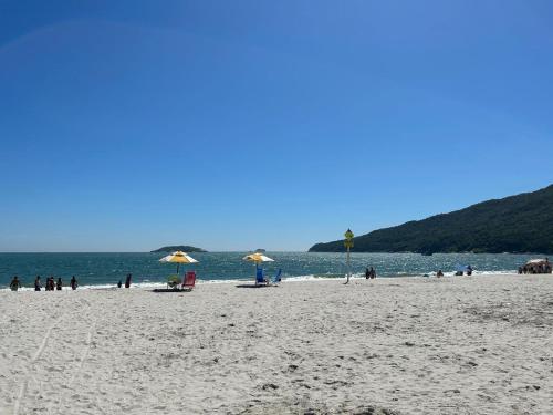 un gruppo di persone su una spiaggia con ombrelloni di Golfinhos Apart Hotel a Florianópolis