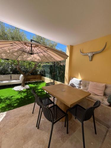 une salle à manger avec une table, des chaises et un parasol dans l'établissement Appartement avec jardin, presqu'île de Giens, à Hyères