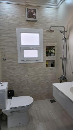 a bathroom with a toilet and a sink and a window at 4 bedroom Yasmin Garden in Barka
