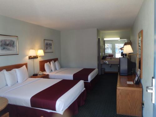 a hotel room with two beds and a television at Americas Best Value Inn Saint Ignace in Saint Ignace
