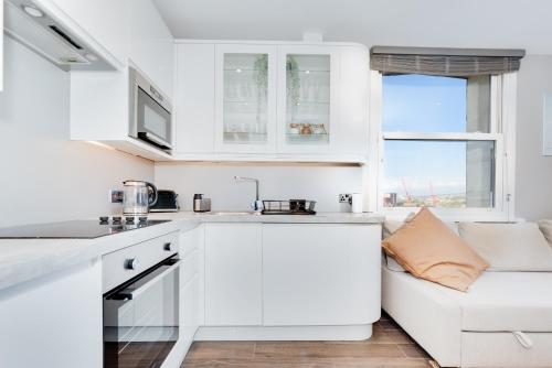 a kitchen with white cabinets and a couch at Cosy Retreat with Views of Brighton City and Sea in Brighton & Hove