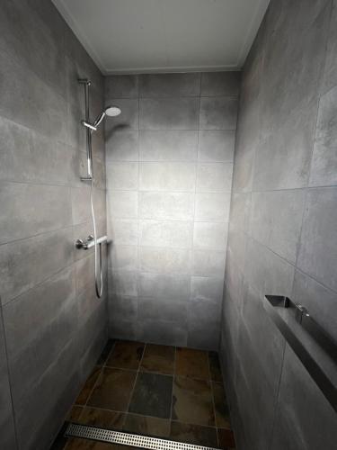 een badkamer met een douche en een betegelde muur bij Vakantiehuisjes Marsherne in Poppingawier