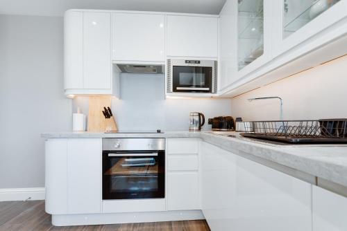 a kitchen with white cabinets and an oven at Cosy Retreat with Views of Brighton City and Sea in Brighton & Hove