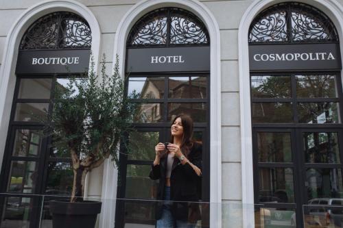 Cosmopolita Boutique Hotel في تيميشوارا: امرأة تقف أمام الفندق
