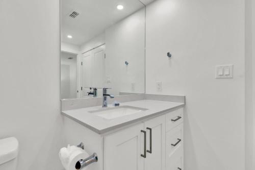 a white bathroom with a sink and a mirror at Spectacular Ocean-View Condo in Beachfront Resort in South Padre Island