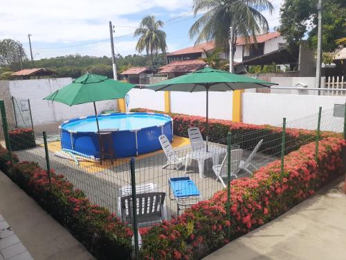 uma piscina com dois guarda-sóis e uma mesa e cadeiras em Casa de Praia Veraneio em Maceió