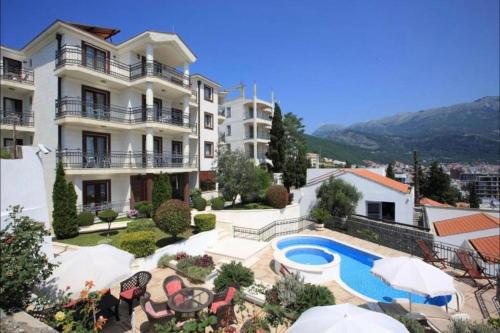 a large apartment building with a swimming pool and patio furniture at Vidikovac Budva in Budva