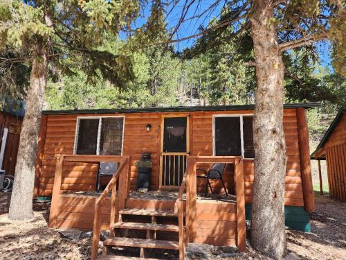 uma cabina de madeira com uma escada que conduz à porta em Allen Gulch Cabins em Hill City