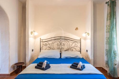 una camera da letto con un letto blu e asciugamani di domo historica sedini a Sedini