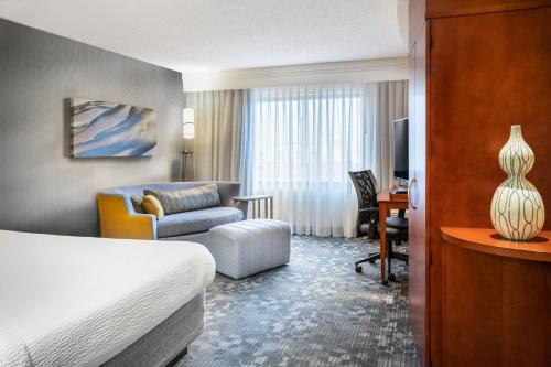 a hotel room with a bed and a chair and a desk at Courtyard by Marriott Denton in Denton