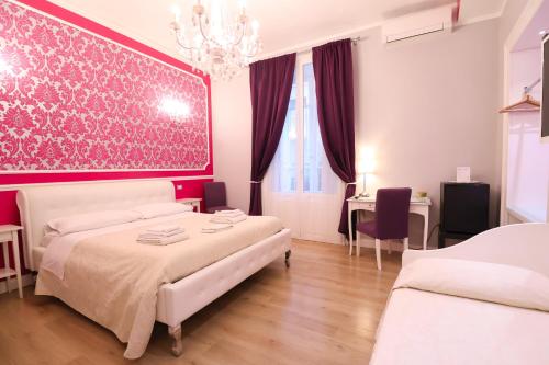 1 Schlafzimmer mit 2 Betten und einer rosa Wand in der Unterkunft Opera Relais in Messina