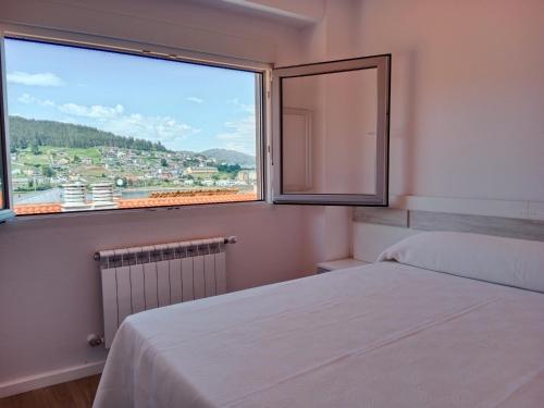 ein Schlafzimmer mit einem Bett und einem großen Fenster in der Unterkunft Atico en La Ría in Vivero