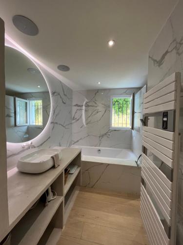 La salle de bains est pourvue d'une grande baignoire et d'un lavabo. dans l'établissement Appartement avec jardin, presqu'île de Giens, à Hyères