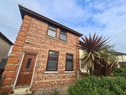 a brick house with a brown door and a palm tree at Emergency - Bedrooms Only in Birkenhead