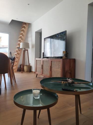 un salon avec une table et une télévision dans l'établissement Appartement sur Terrasse, à Capbreton