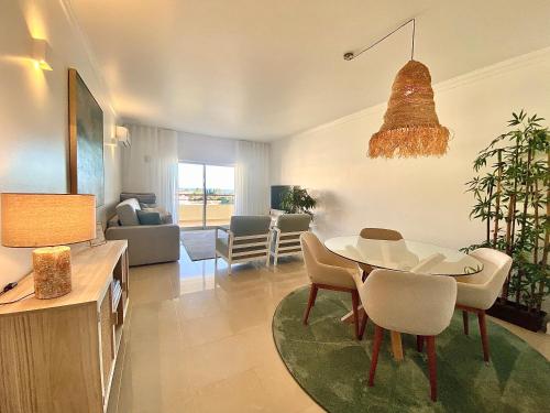 een woonkamer met een tafel en stoelen en een eetkamer bij Vilamoura Avelãs Ocean View Apartment in Vilamoura
