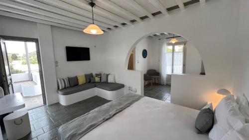 a white bedroom with a bed and a couch at Myrto Bungalows in Artemonas