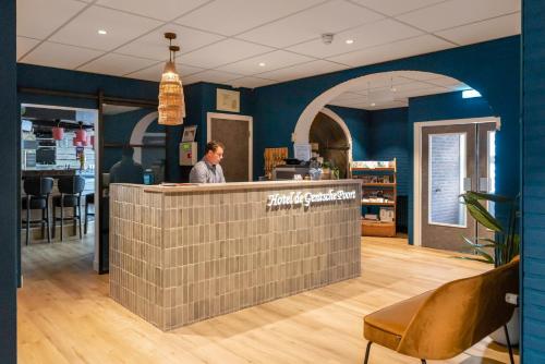 a man standing at the counter of a restaurant at Hotel de Gentsche Poort in Biervliet