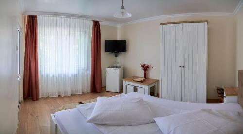 a bedroom with a white bed and a television at Pension Charisma in Băile Herculane