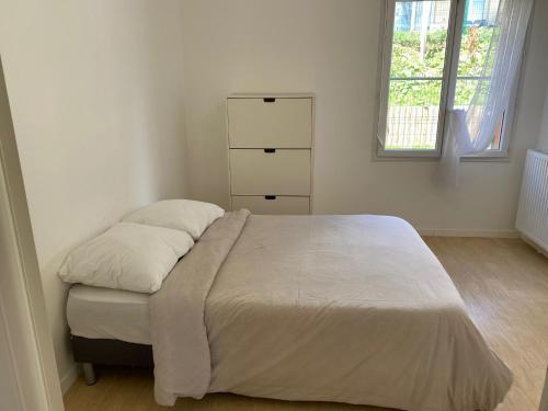 1 dormitorio con 1 cama con 2 almohadas y vestidor en Jolie T2 proche de Paris et du Stade De France, en Pierrefitte-sur-Seine