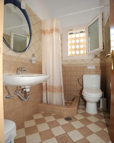 a bathroom with a sink and a toilet and a mirror at Tinos View Apartments in Tinos