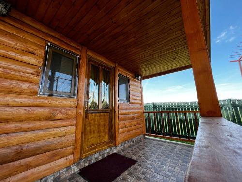 a wooden cabin with a door and a balcony at Pensiunea Colt de Rai, Vistisoara in Stațiunea Climaterică Sâmbăta