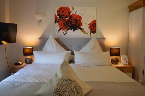 a bedroom with two white beds with red flowers on the wall at Landhaus Zum Heidewanderer mit THERMEplus in Bad Bevensen
