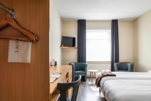 a hotel room with a bed and a desk and chairs at Hotel de Gentsche Poort in Biervliet