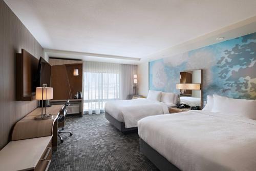 a hotel room with two beds and a desk at Courtyard Dallas Grand Prairie in Grand Prairie