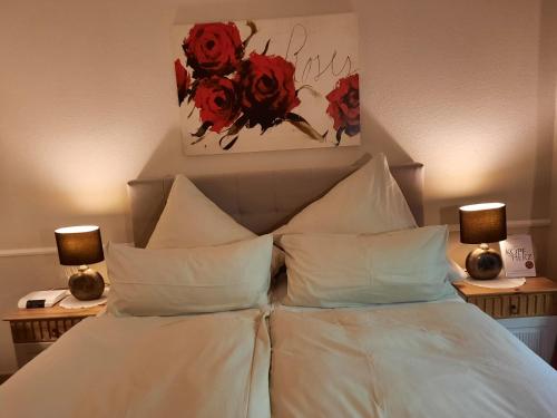 a bed with white pillows and red flowers on the wall at Landhaus Zum Heidewanderer mit THERMEplus in Bad Bevensen
