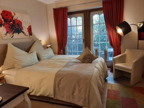 a bedroom with a bed with red curtains and a chair at Landhaus Zum Heidewanderer mit THERMEplus in Bad Bevensen