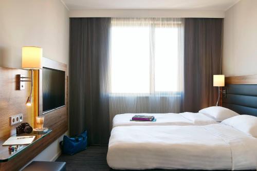 a hotel room with two beds and a large window at Moxy Ludwigshafen in Ludwigshafen am Rhein