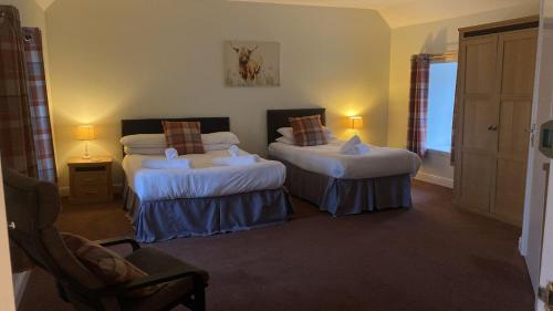 una habitación de hotel con 2 camas y una silla en The First & Last Inn, en Eyemouth
