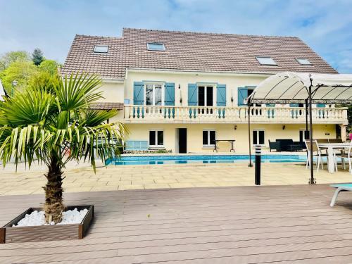 a house with a palm tree in a courtyard at Appartement 120m2 dans maison avec piscine in Boissy-lʼAillerie