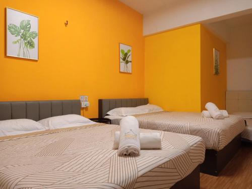 2 camas en una habitación con paredes amarillas en Cozy Private Family Room in Bayan Lepas, en Bayan Lepas