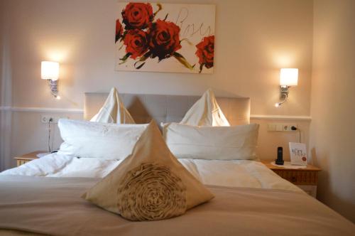 a bedroom with a bed with white sheets and red flowers at Landhaus Zum Heidewanderer mit THERMEplus in Bad Bevensen