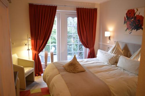 a bedroom with a large bed with red curtains at Landhaus Zum Heidewanderer mit THERMEplus in Bad Bevensen