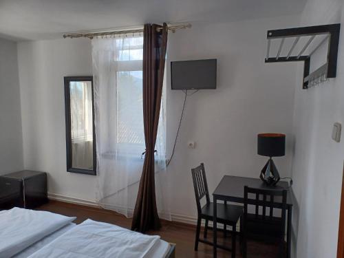a bedroom with a bed and a table and a window at Vila Oltețul in Predeal